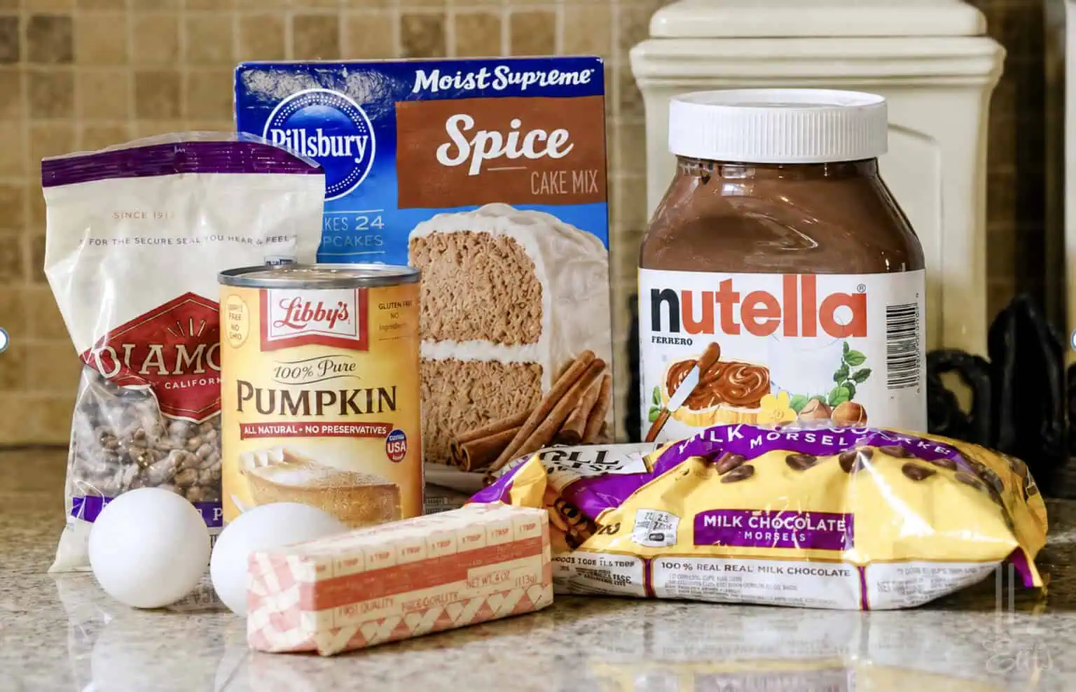 pumpkin earthquake cake ingredients on a counter, including spice cake mix, nutella, and pecans.