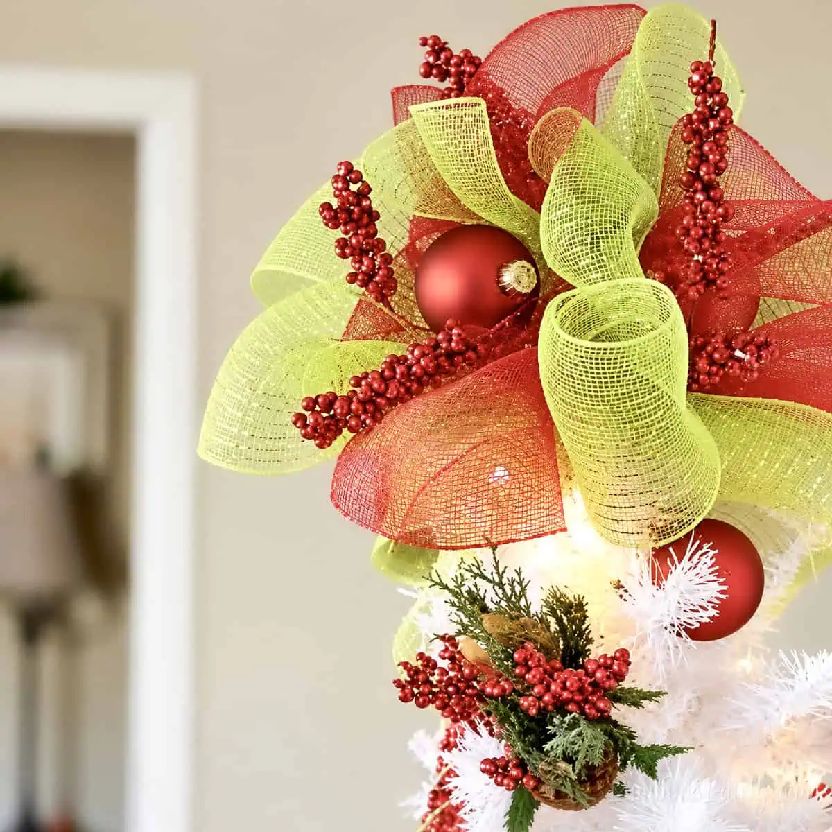 red and green diy tree topper on top of a white christmas tree.