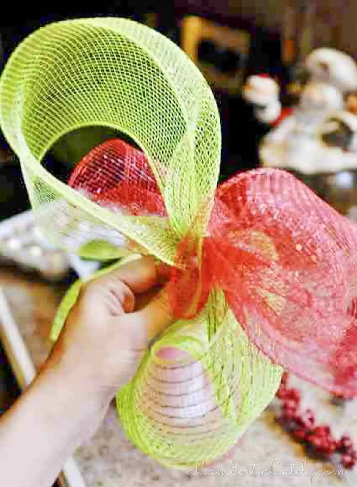 Crossed red and green deco mesh bows forming the base of DIY tree topper.