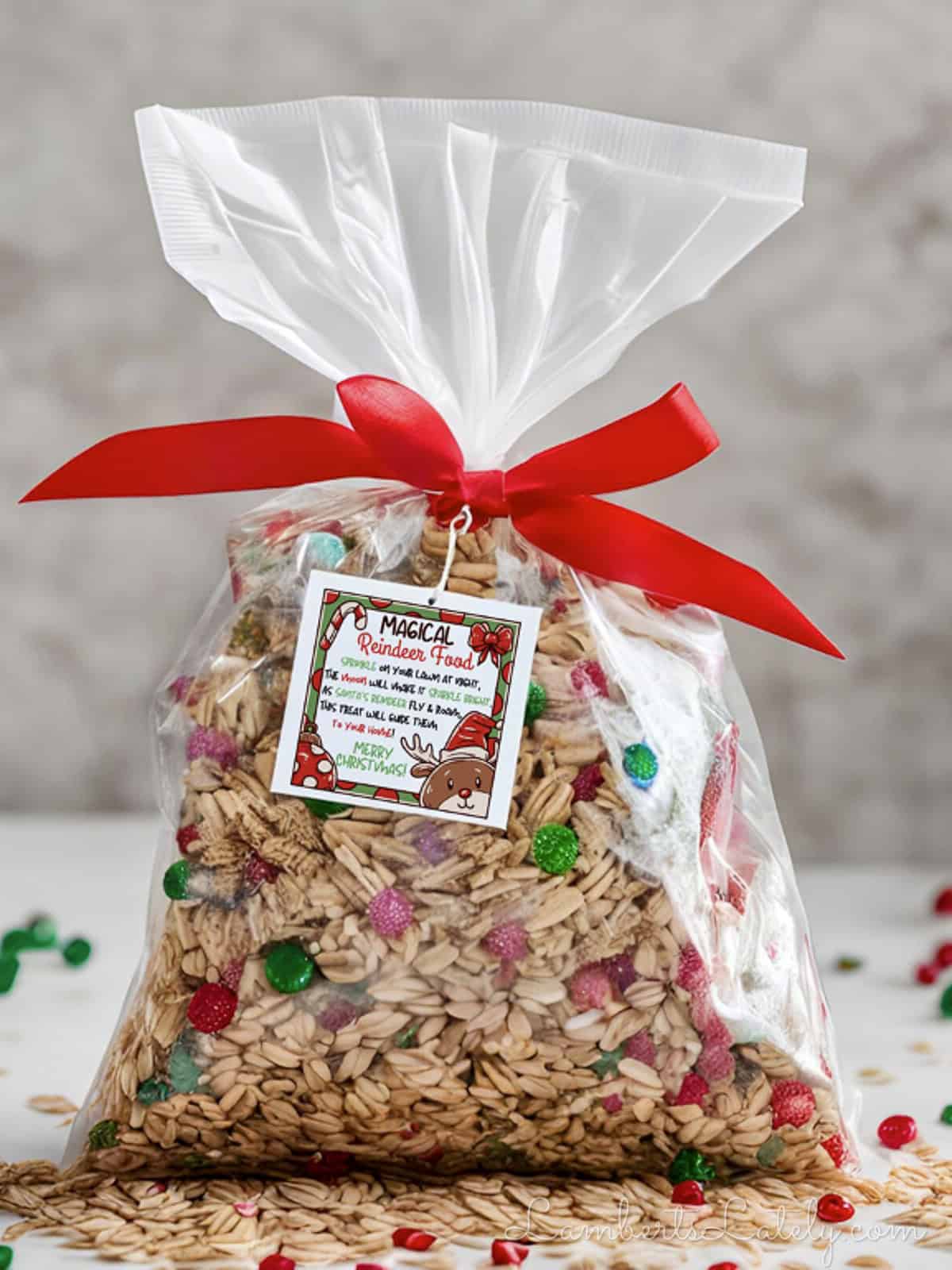 Festive reindeer food in a clear bag with red ribbon and holiday decorations.