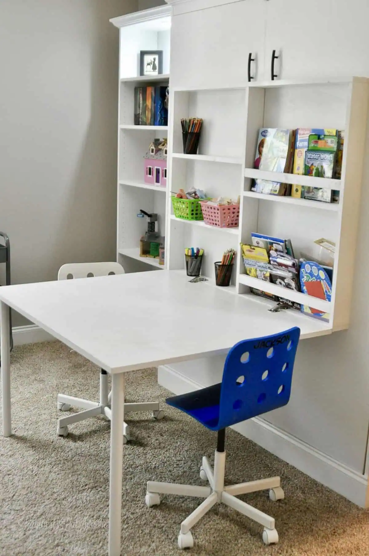 white vertical murphy bed (full size) with ikea billy bookcase side cabinets and a fold-out desk with chairs.