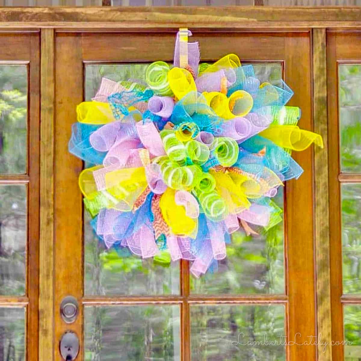 colorful deco mesh wreath hanging on a wood door.