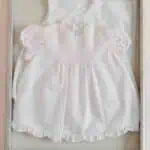 White baby dress displayed in a shadow box for DIY newborn keepsake.