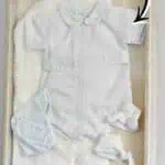 Baby's first outfit framed in a shadow box with socks and accessories.