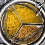 Variety of uncooked pasta in a steamer basket for instant pot cooking.
