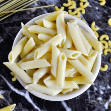 bowl of penne pasta on a black countertop.