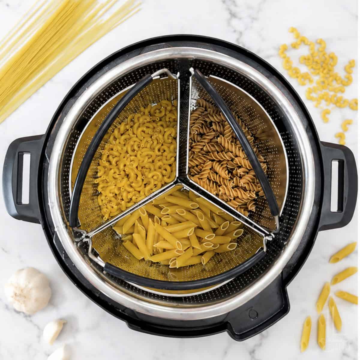 Trio of cooked pasta types in a steamer basket for Instant Pot cooking.