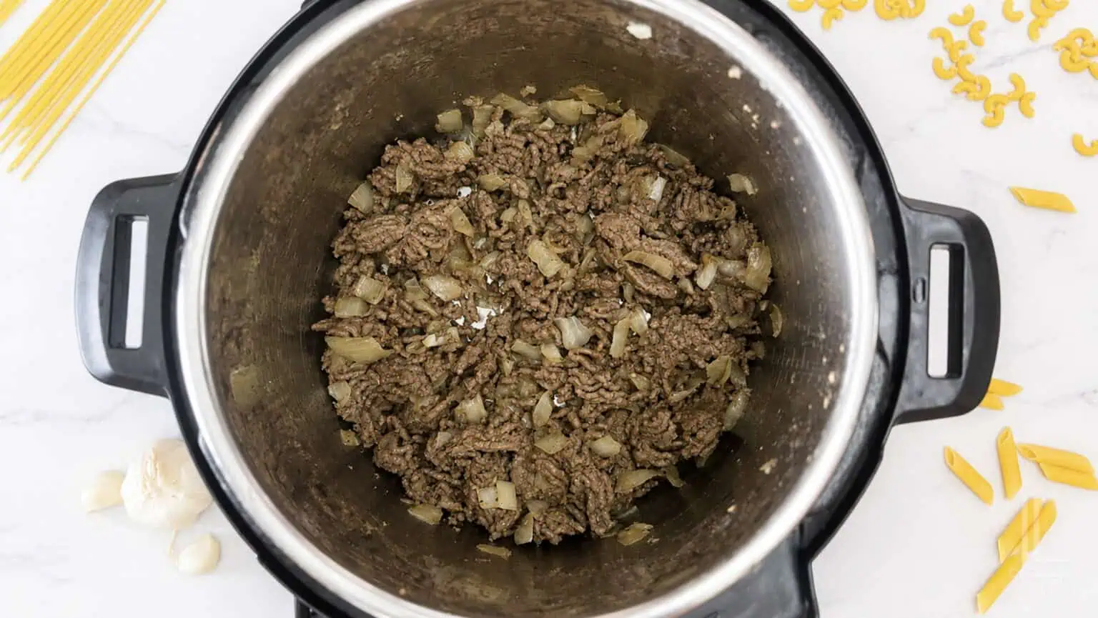 Ground beef and onions cooking in an Instant Pot for pasta recipe.