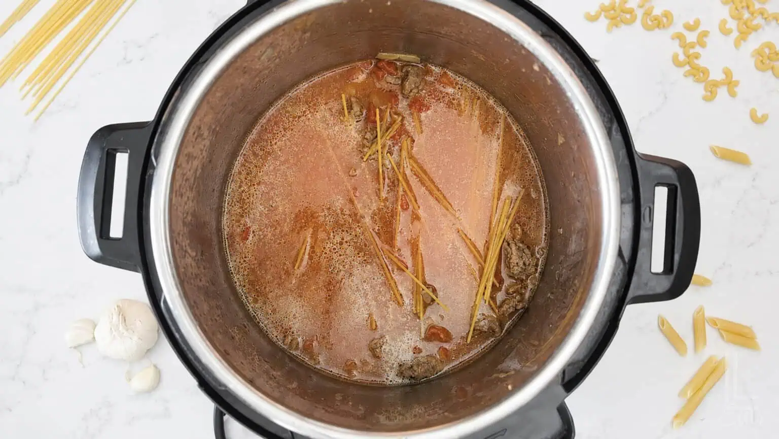 Cooking pasta in an Instant Pot with tomato sauce and spaghetti noodles, with extra water.
