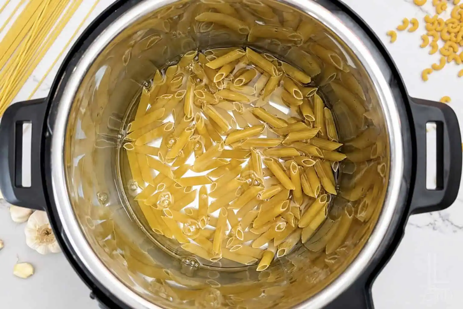 Uncooked pasta with water in an Instant Pot for easy pasta cooking.