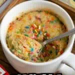 Close-up of vanilla microwave mug cake with colorful sprinkles in a white mug.