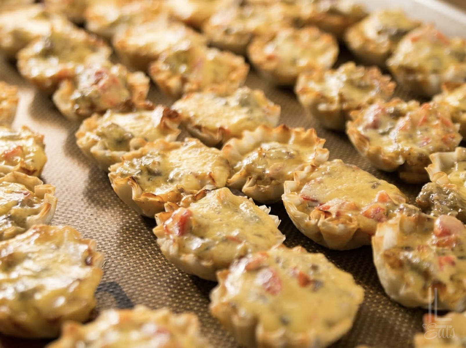 cooked sausage rotel cups on a baking sheet.