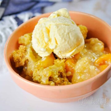 bowl of peach cobbler in front of a blue striped towel.