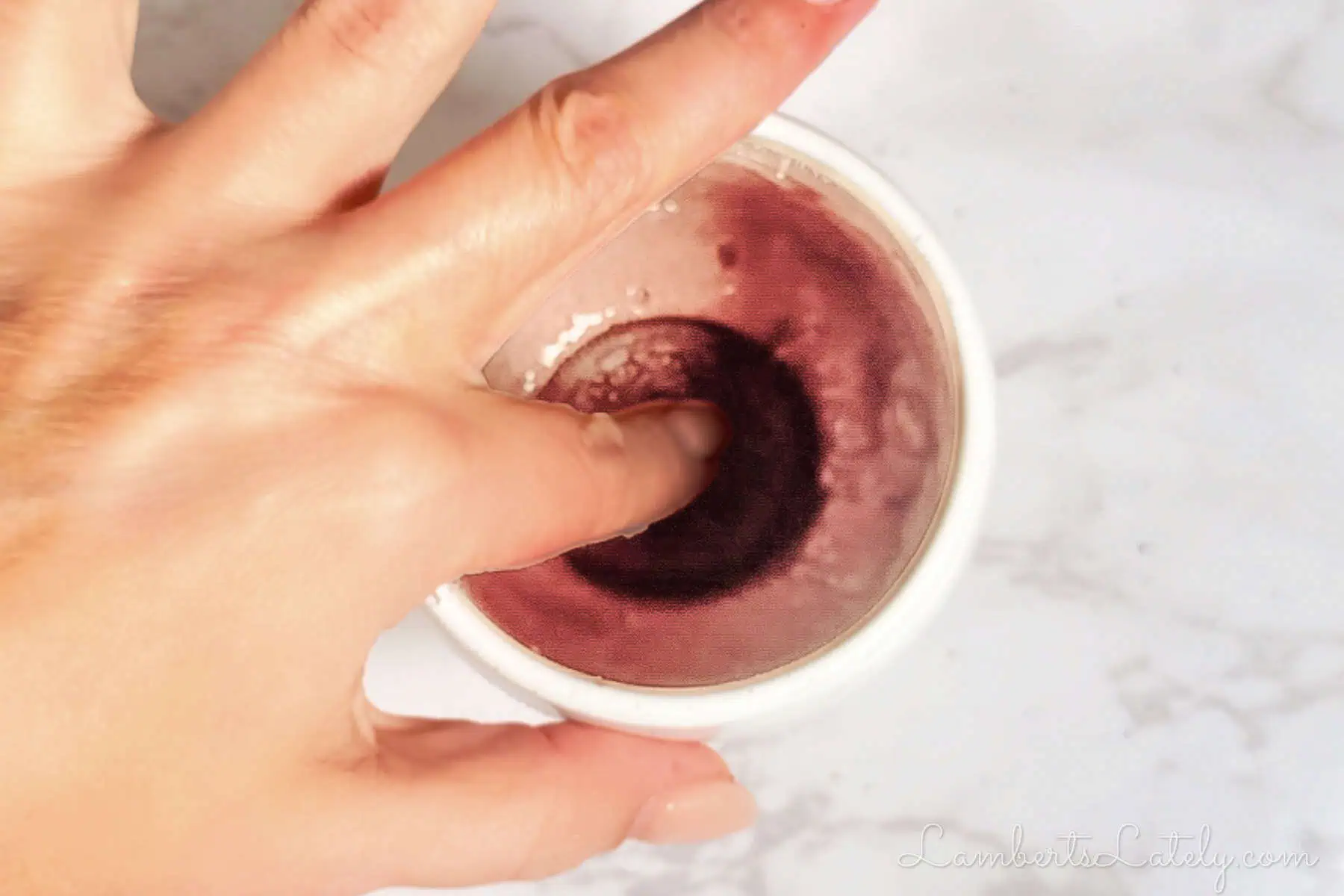 pressing a cookie into batter in a cup.