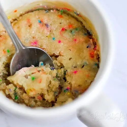 mug cake with sprinkles, with a spoon.