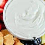 Cream cheese dip in a bowl with strawberries and crackers around it.