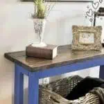 DIY console table with a wooden top, blue legs, and decorative items on top.