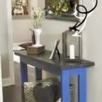 DIY console table with a dark wood top and blue legs, decorated with plants and accessories.