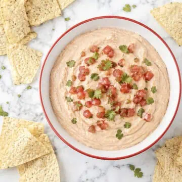 Cream cheese and salsa dip garnished with cilantro, served with tortilla chips.