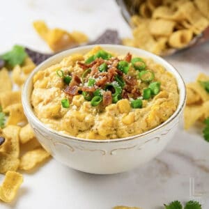 Creamy crock pot crack corn dip garnished with green onions and bacon bits.