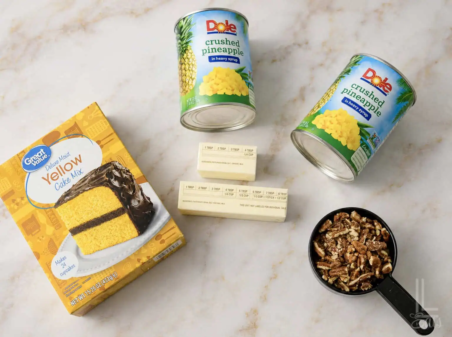 Ingredients for pineapple dump cake with crushed pineapple, yellow cake mix, and pecans.