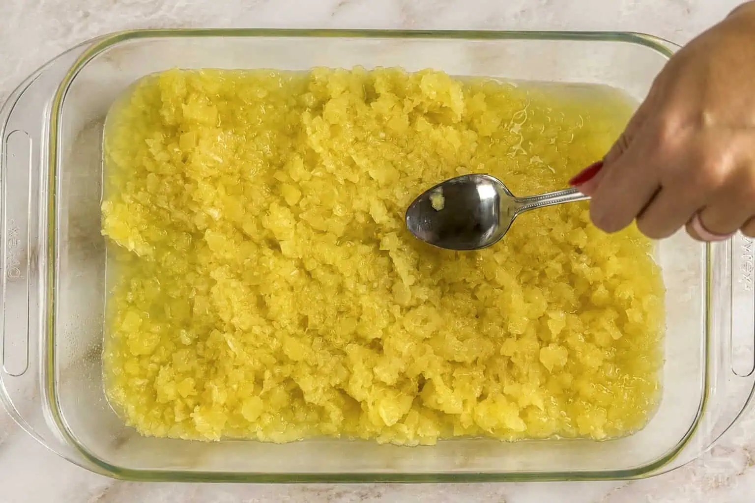 spreading crushed pienapple with heavy syrup in a 9x13 baking dish.