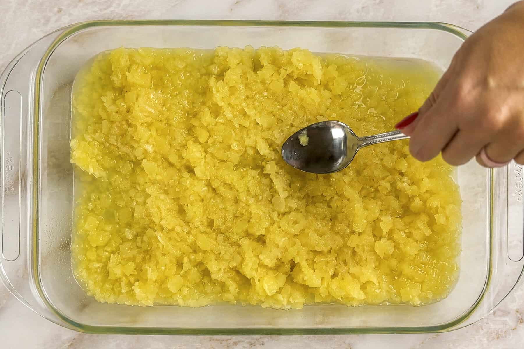 spreading crushed pienapple with heavy syrup in a 9x13 baking dish.