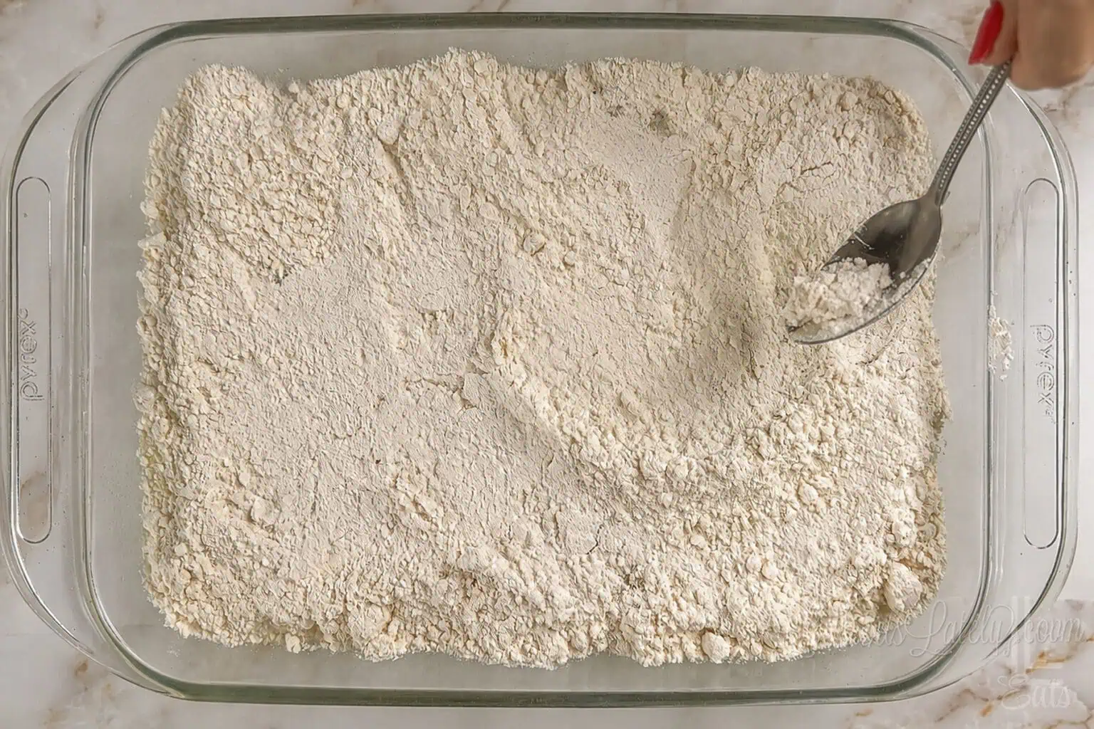 spreading cake mix on top of crushed pineapple in the baking dish.