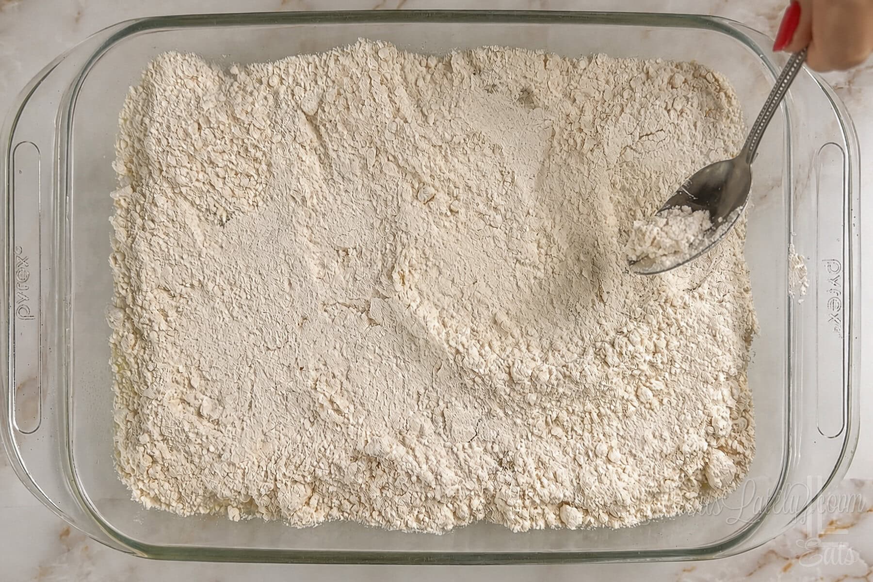 spreading cake mix on top of crushed pineapple in the baking dish.