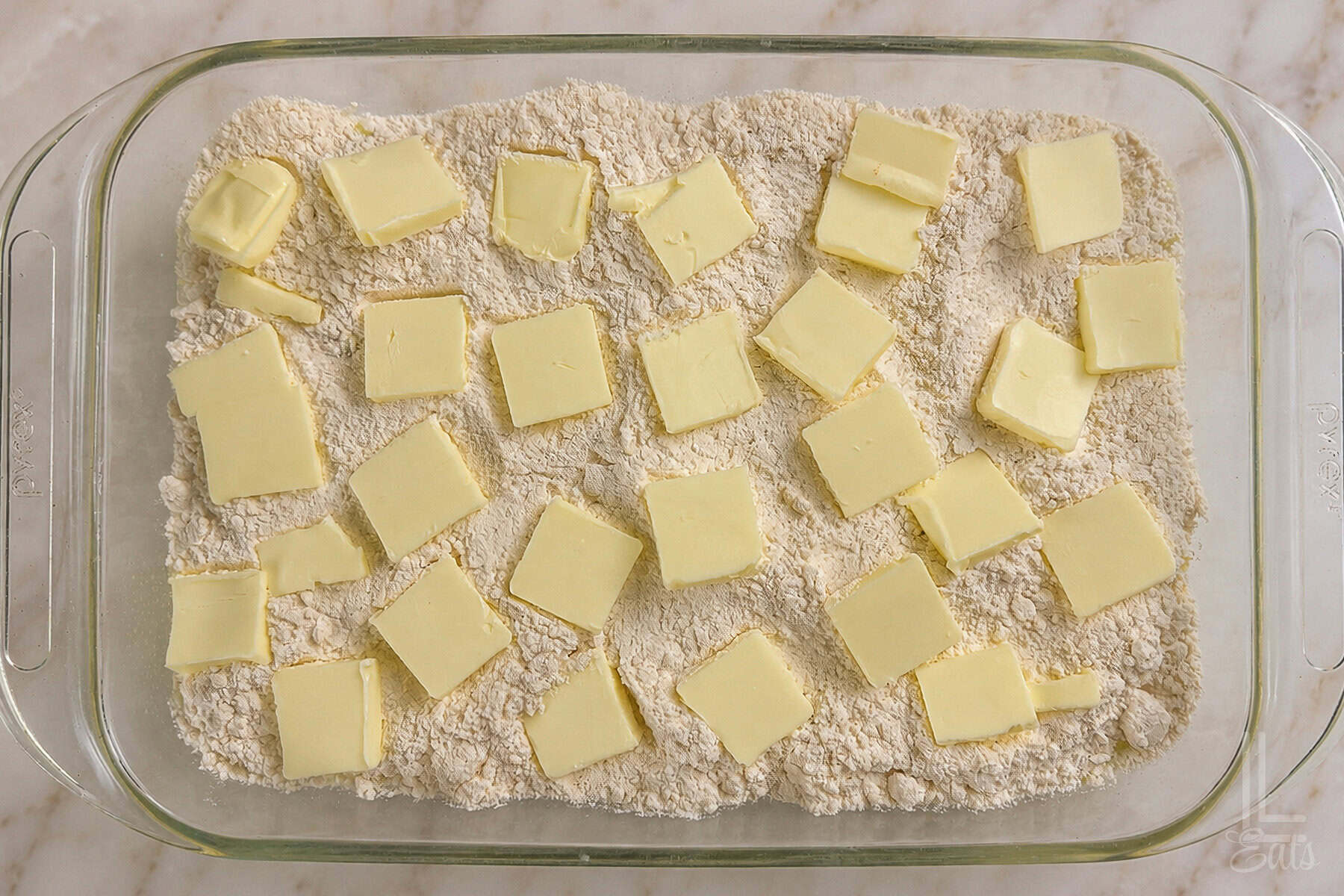 pats of butter on top of dry cake mix in a baking dish.