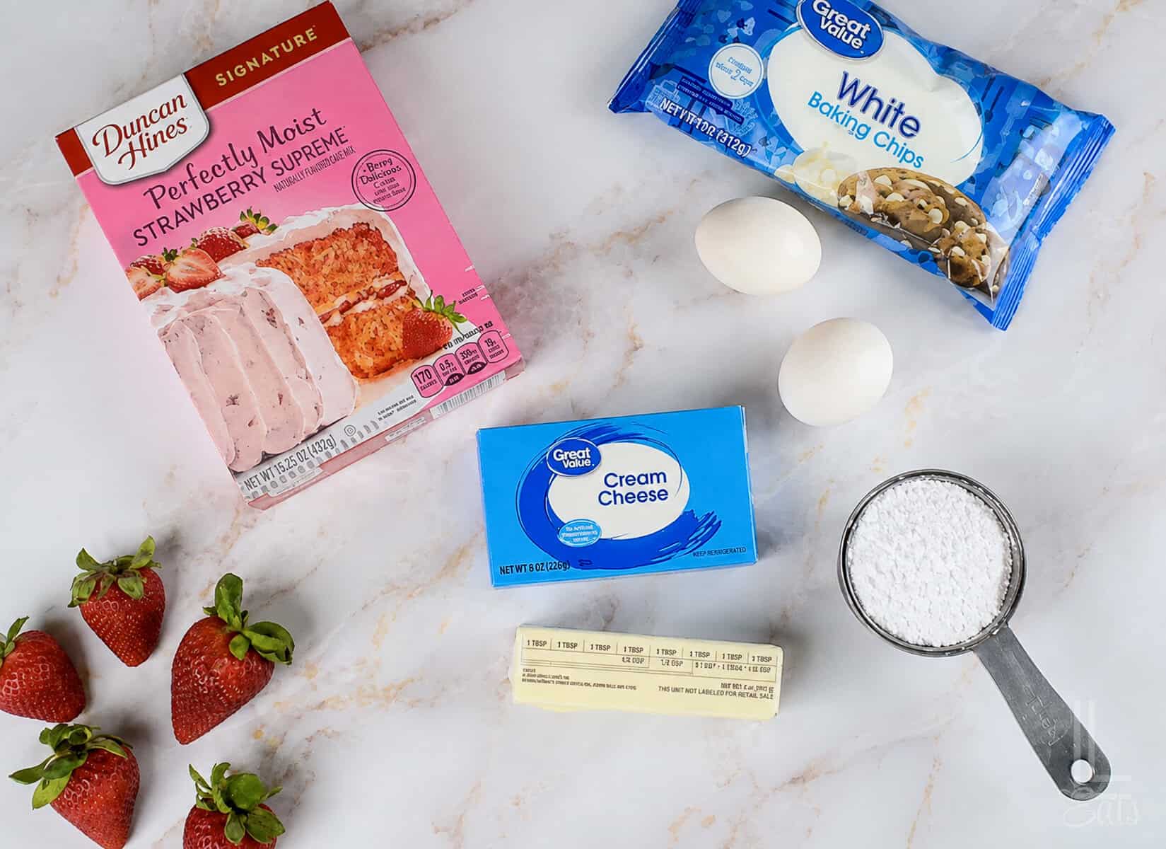 Ingredients for strawberry cheesecake cookies with cake mix, including strawberries, cream cheese, & white chocolate chips.