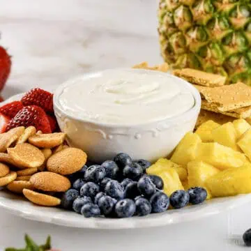 sweet cream cheese fruit dip in a bowl, surrounded by fruits and sweet crackers.