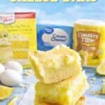 Lemon cream cheese bars with cake mix, fresh lemons, and eggs on a blue background.
