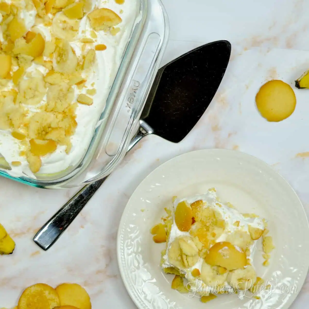 baking dish of banana pudding poke cake and a slice on a plate, with serving utensil.