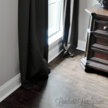 bottom of brown hemmed curtain panels hung on a window next to table.