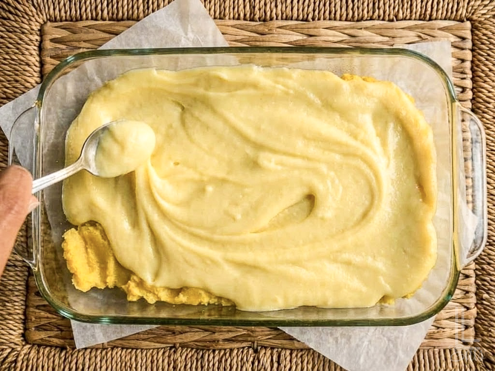 spreading the cream cheese layer of lemon chess bars with a spoon.