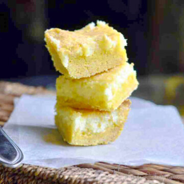 lemon chess bars stacked on a piece of parchment paper.