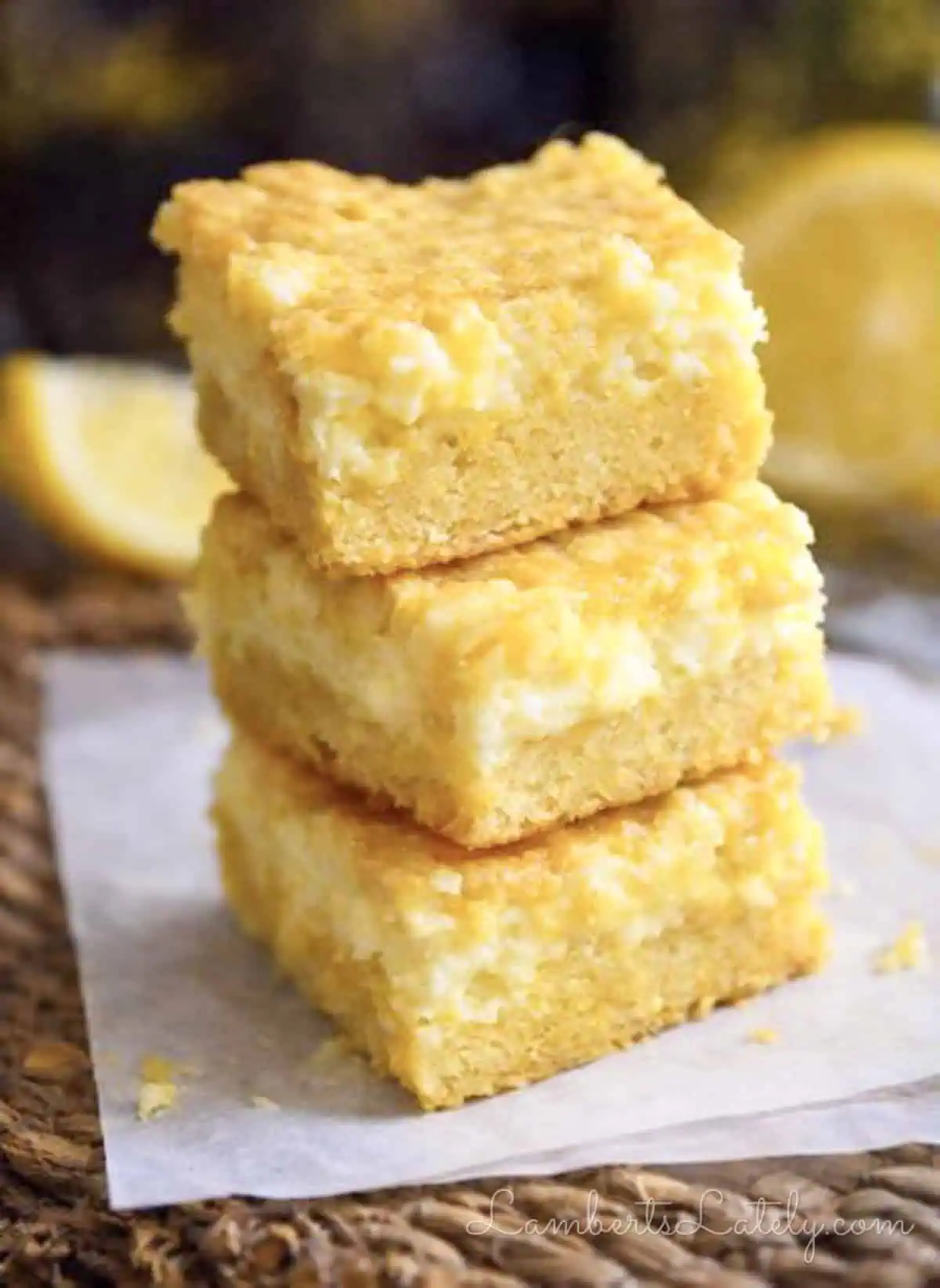 lemon chess bars stacked on a piece of parchment paper.