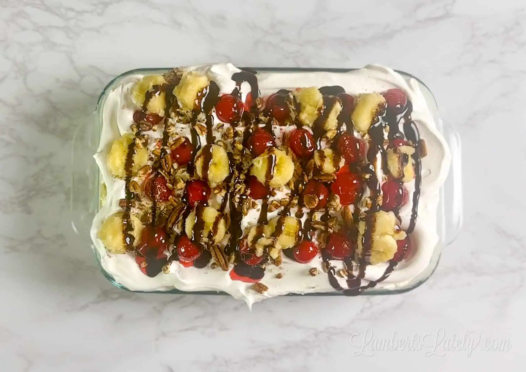 banana split ingredients spread over top of banana split cake.