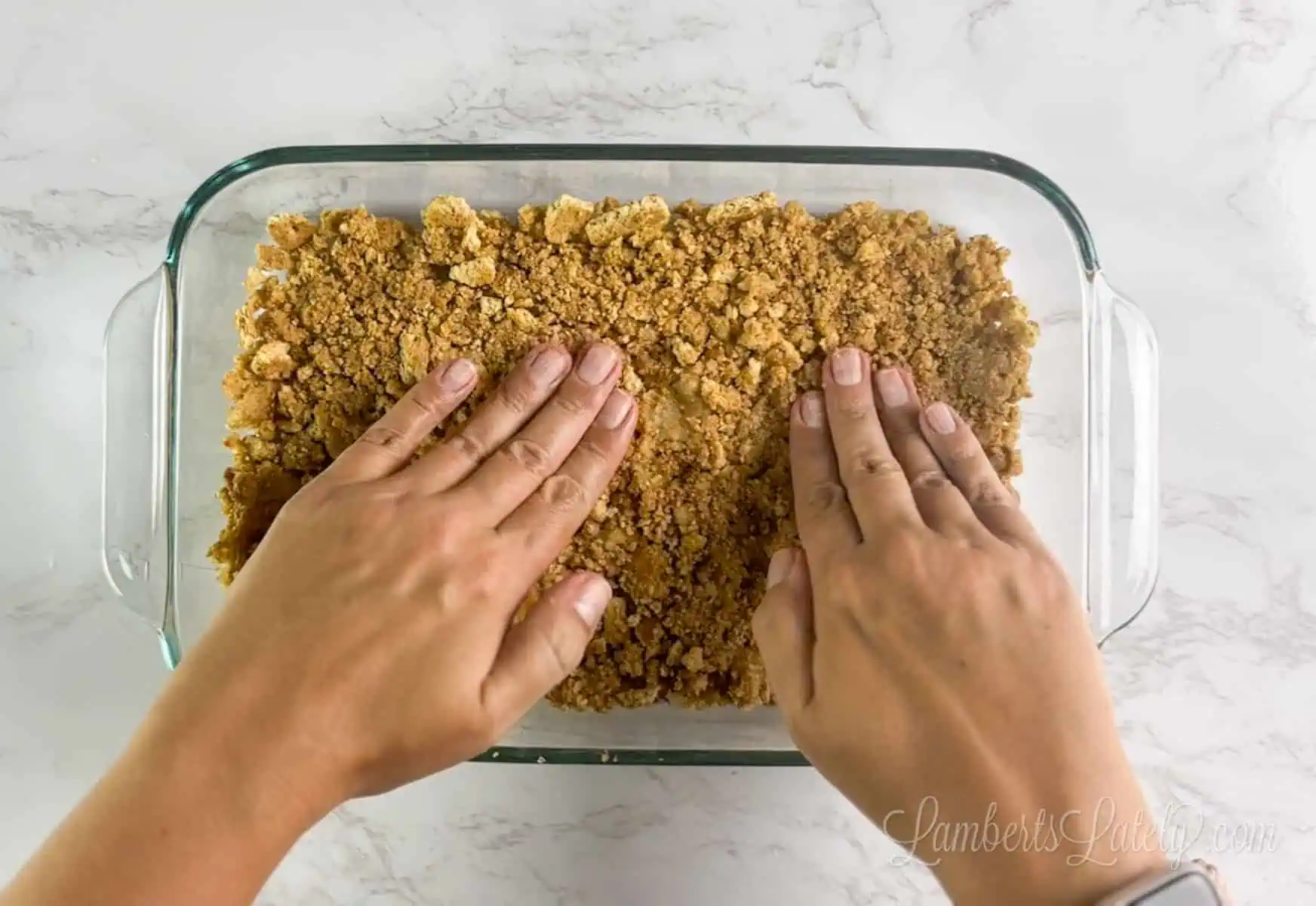pressing graham cracker crust into a glass baking dish.
