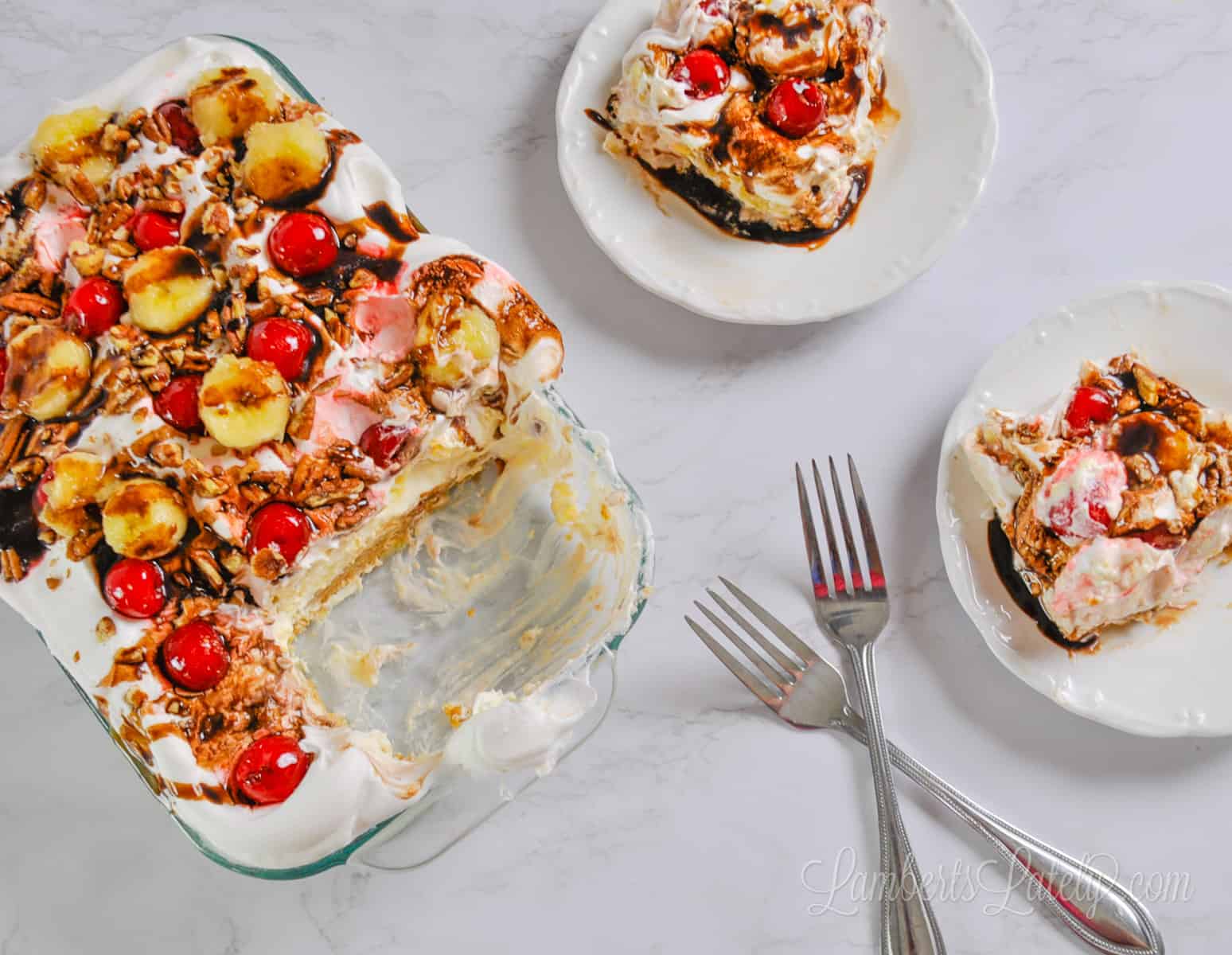 banana split cake in a baking dish, with two plates and slices, and forks.