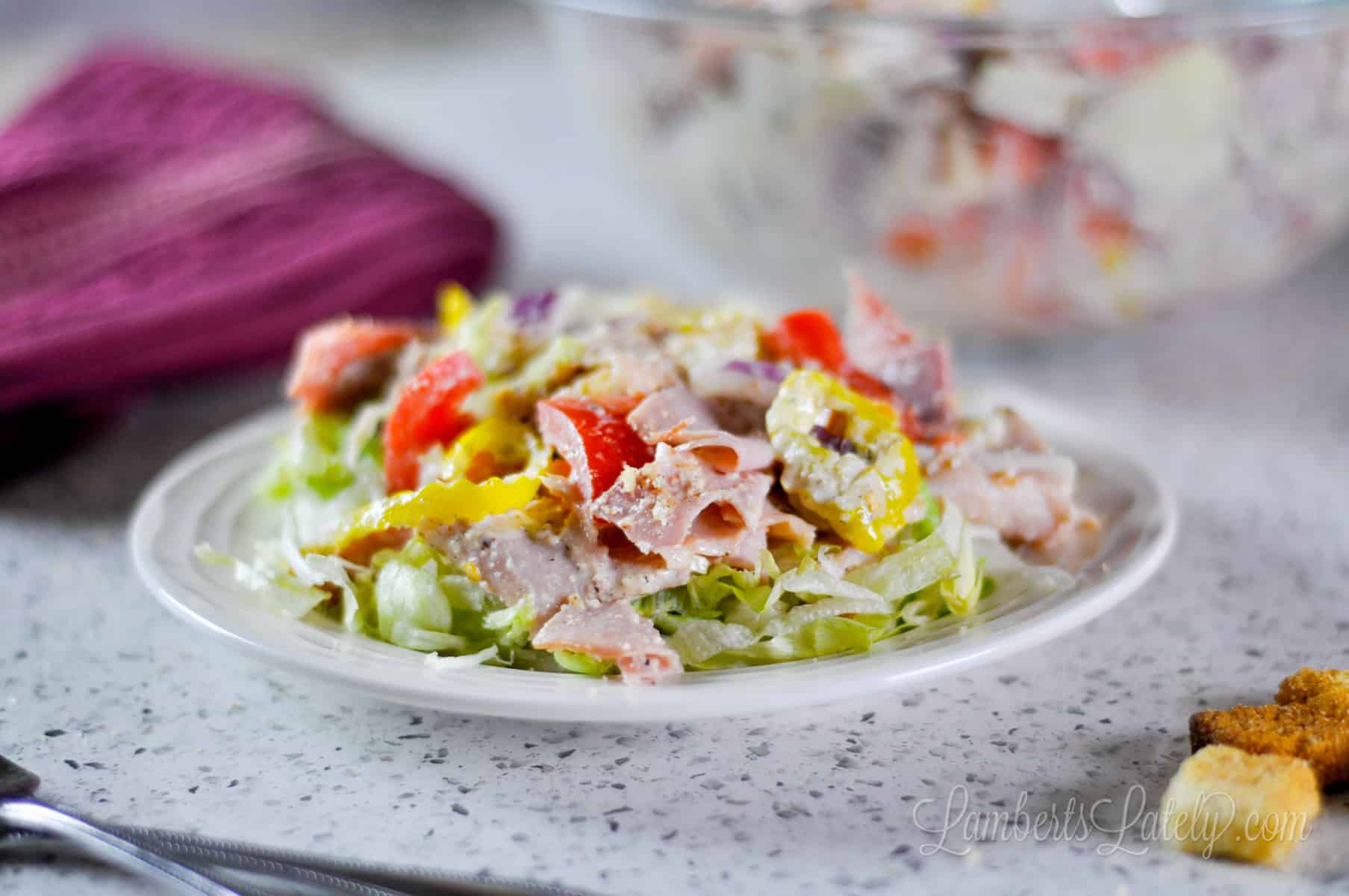 italian grinder salad mix over a bed of lettuce on a plate.