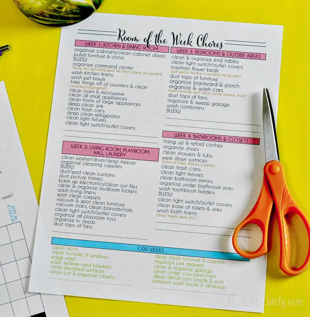 Room of the week chores list from the printable cleaning schedule sitting next to orange scissors on a bright yellow background.