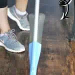 Person cleaning vinyl plank flooring with a spray mop for daily maintenance.