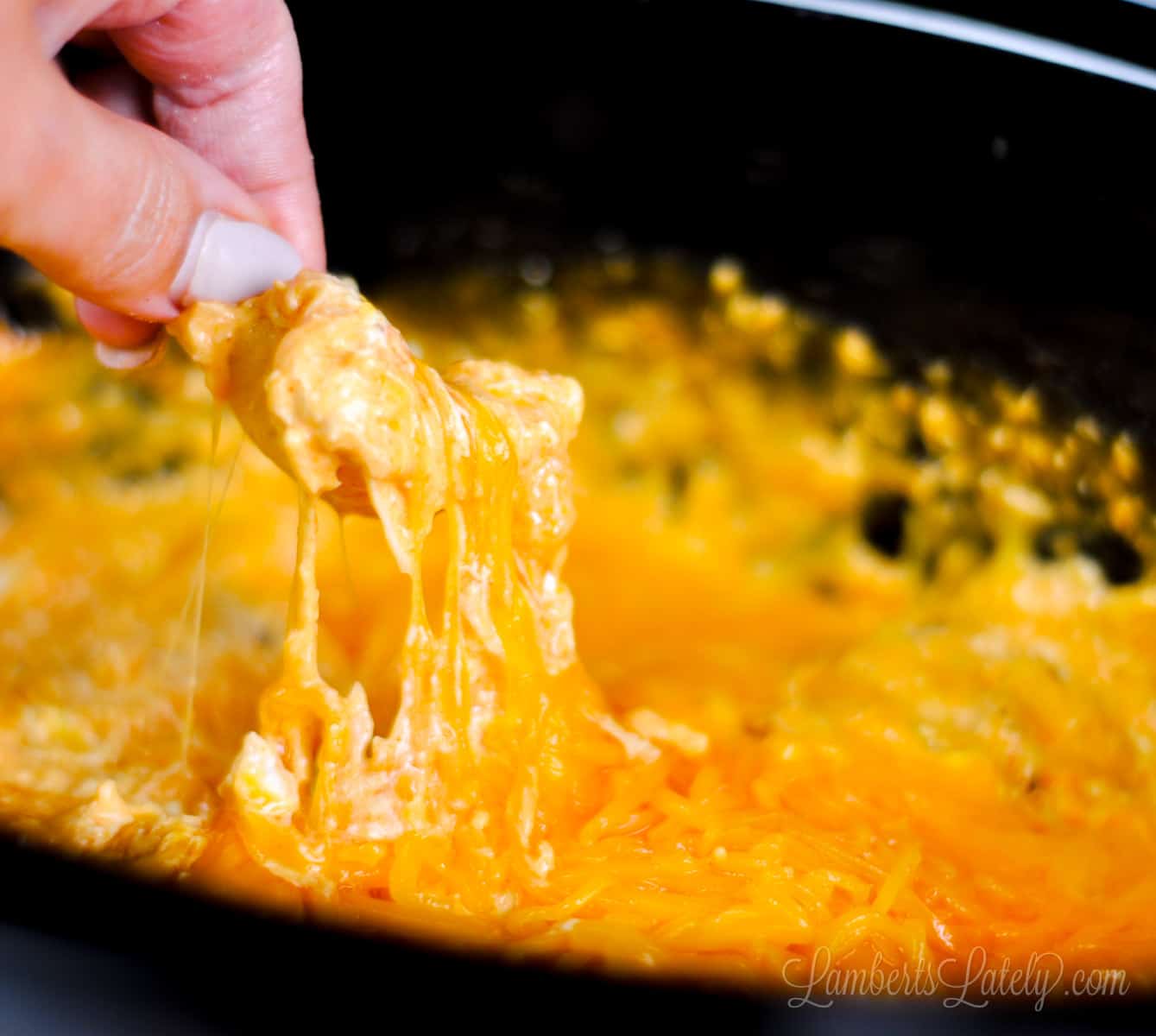 scooping buffalo chicken dip out of crock pot with a tortilla chip.