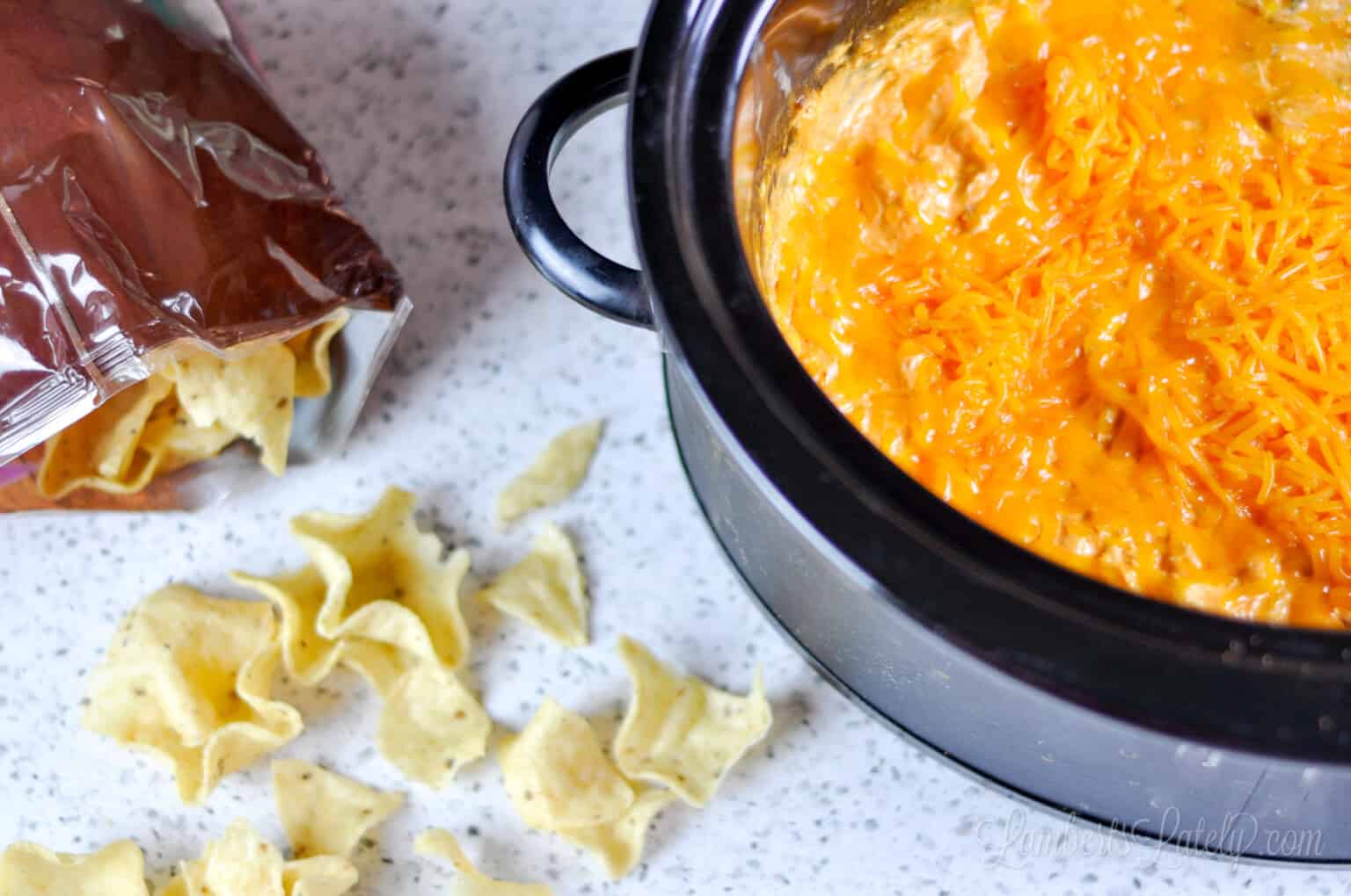crock pot of buffalo chicken dip with tortilla chips on a counter.