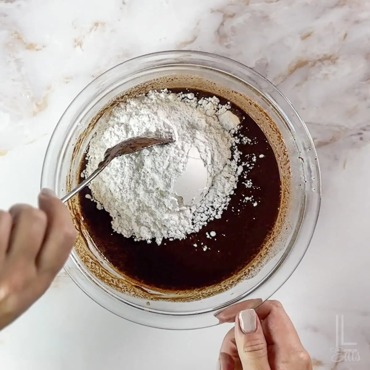 adding powdered sugar to the chocolate dip mixture in a glass bowl.