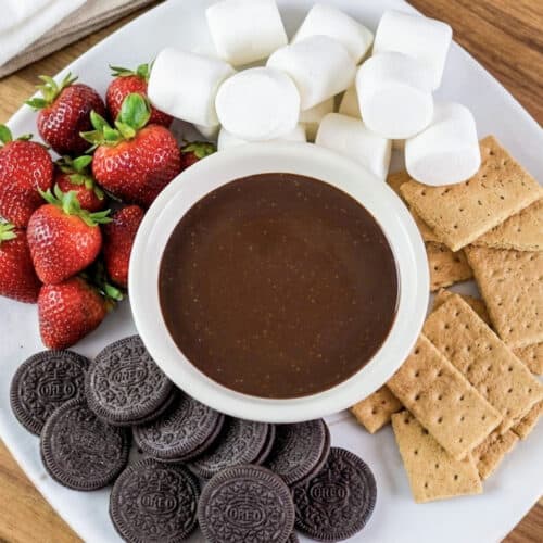 a tray of dippers (strawberries, marshmallows, graham crackers, and oreo cookies) with a bowl of smooth chocolate dip in the middle.