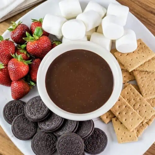 a tray of dippers (strawberries, marshmallows, graham crackers, and oreo cookies) with a bowl of smooth chocolate dip in the middle.