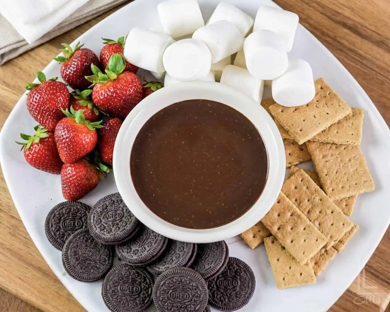 a tray of dippers (strawberries, marshmallows, graham crackers, and oreo cookies) with a bowl of smooth chocolate dip in the middle.